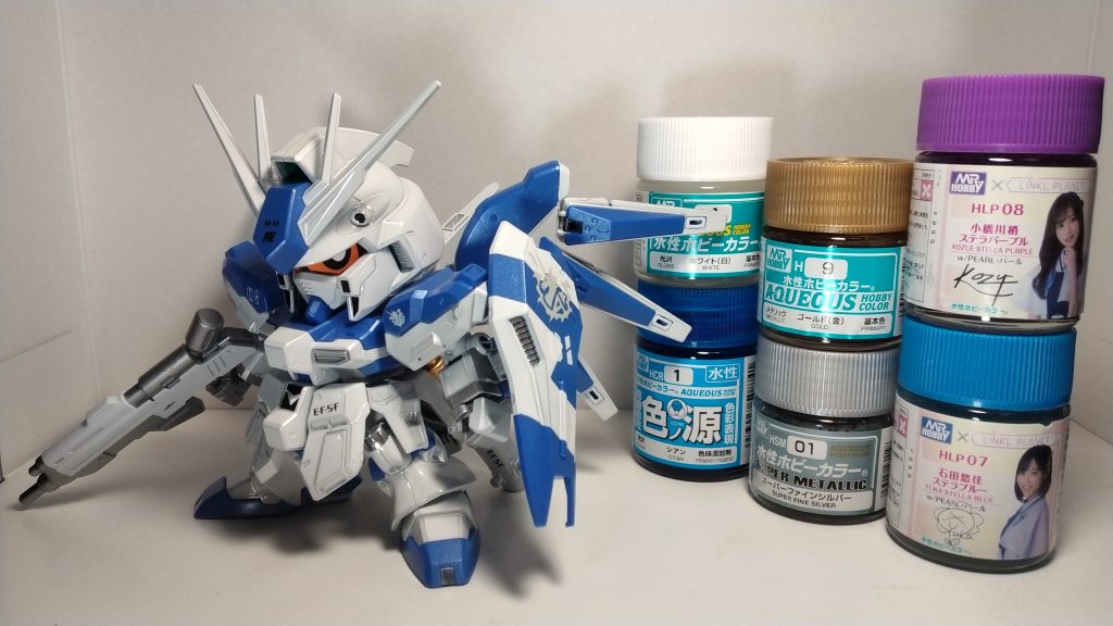 使用した塗料と一緒に記念撮影！今回は発売されたばかりの水性ホビーのパールカラーが大活躍でした(zaku-kao5)ブルーとパープルを3：1くらいで混ぜて、青地の成型色にそのまま塗りました。それでも良い感じでテカってくれたので大満足です(gandam-hand2)元々青い機体に間に合わせようと作っていたのですが、夏休みの宿題のごとくギリギリで間に合わなかったので、RX-93の日にはなんとか完成です(gandam-hand1)それでは皆さん最後まで閲覧して頂きありがとうございました！！