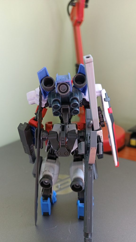 En el apartado trasero cuenta con una mochila de alta potencia para cargas directas, junto a unos propulsores móviles para no perder maniobrabilidad.Conectado al faldón trasero se encuentra el armamento, para corto alcance una espada tipo sable y para el ataque a distancia un rifle de proyectiles sólidos.