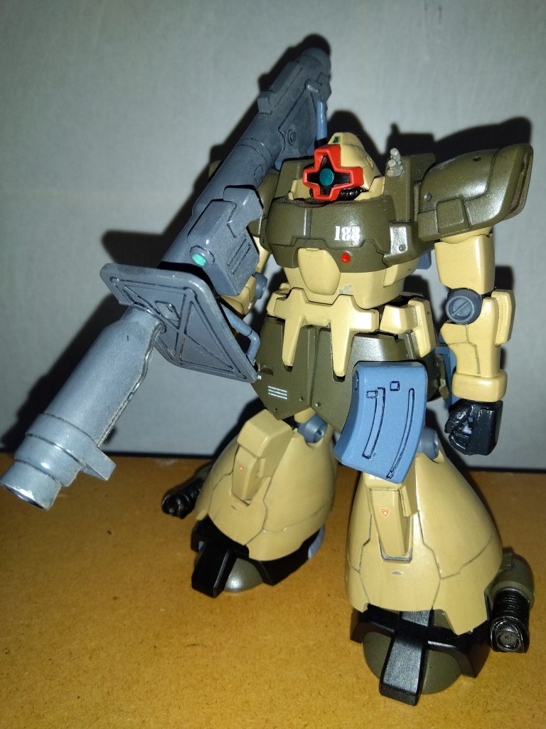 　主人公、サム・ハーバート伍長機の正面素立ちです。　使用したキットはHGUCドムトローペン　サンドブラウンです。　基本塗装はライトブラウンとオリーブドラブです。　本来ならライトブラウンとココアブラウンで塗装されているのですが、このキットを製作した当時「茶色よりオリーブドラブの方が絶対カッコいいだろ！」と思って、この色に塗装しました。関節や手首はミッドナイトブルー、ヒジやヒザのマルイチモールドはニュートラルグレーにツヤ消し黒を混ぜたいつもの暗いグレーです（いずれも水性ホビーカラー）。　仕上げにモノアイと頭部サブカメラをマスキングテープで保護してから、ツヤ消しスプレーでトップコートを吹きました。　ちなみに、スミ入れはいつも通りシャープペンを使用しています。　　武装はキットに付属するラケーテン・バズと予備弾倉です。　ラケーテン・バズのスコープは、水色に黄色を少し混ぜた淡いエメラルドグリーンで塗ってみました。　ところで、私はこういった砂漠戦用の機体はもれなくウェザリングを施したくなるのですが、今回は「主人公たちに、配備されて間もない新型モビルスーツを貸してくれた気前のいい基地司令」というキャラクターを強調するため、あえてウェザリングを行わずに仕上げました。
