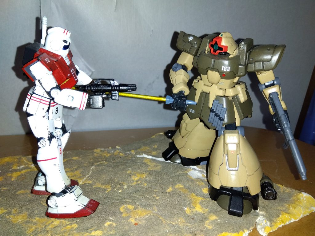 連邦のモビルスーツは小型のビーム兵器を連射しながら、こちらに接近しようとしている。 リリーはそれをかわしながら、牽制でMMP-80 90mmマシンガンを放つ。「どうせアンタらの装甲なら、こんなもん痛くもかゆくもないだろうに、ビビっちゃってまぁ・・・」そう呟きながら相手のモビルスーツ ― 連邦が最近ようやく正式に量産を開始したジム ― に一気に接近し、コクピットにヒートサーベルを突き立てた。「とは言え、これだけ開けた砂漠だと相手に接近するのも一苦労だな・・・そうだ!」