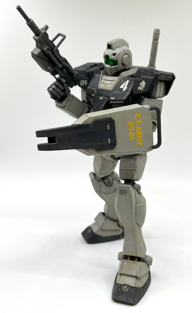 塗装はグレー部はサーフェイサー吹きっぱなし、黒部はつや消し黒です。ホワイトディンゴジムの色は登場メディア間での統一感が無く、もはや黒と灰色っぽければOKレベルという認識です。初出のドリキャスソフトのCG、ないしその説明書の小林源文先生のイラストがWDジムの元祖ですので、そのあたりをイメージソースにして色を塗りました。WD隊マークとシールドのマーキングは、数年前に入手したMGホワイトディンゴジムキャノンに付属していたデカールを使用しました。こういうのは取っておくものですね。