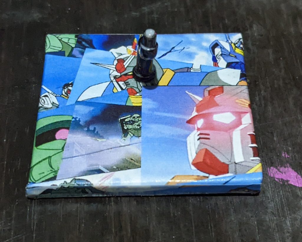 台座は第一話「ガンダム大地に立つ」の場面を散りばめた画像をプリントアウトして貼り付けてあります。