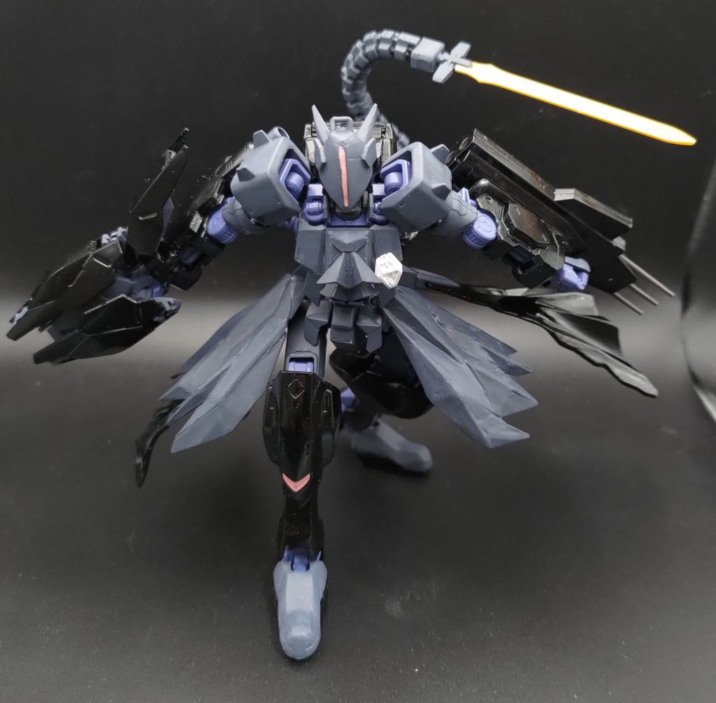 仮面の内側にはガンダムフレームのツインアイがありますが、パイロットの趣味でメインカメラを仮面上に設定し、スリット状に配置しています。背面臀部には多関節アームと蛇腹フレームからなる近接戦闘用ブレード「ギャングウェイ」を装備しています
