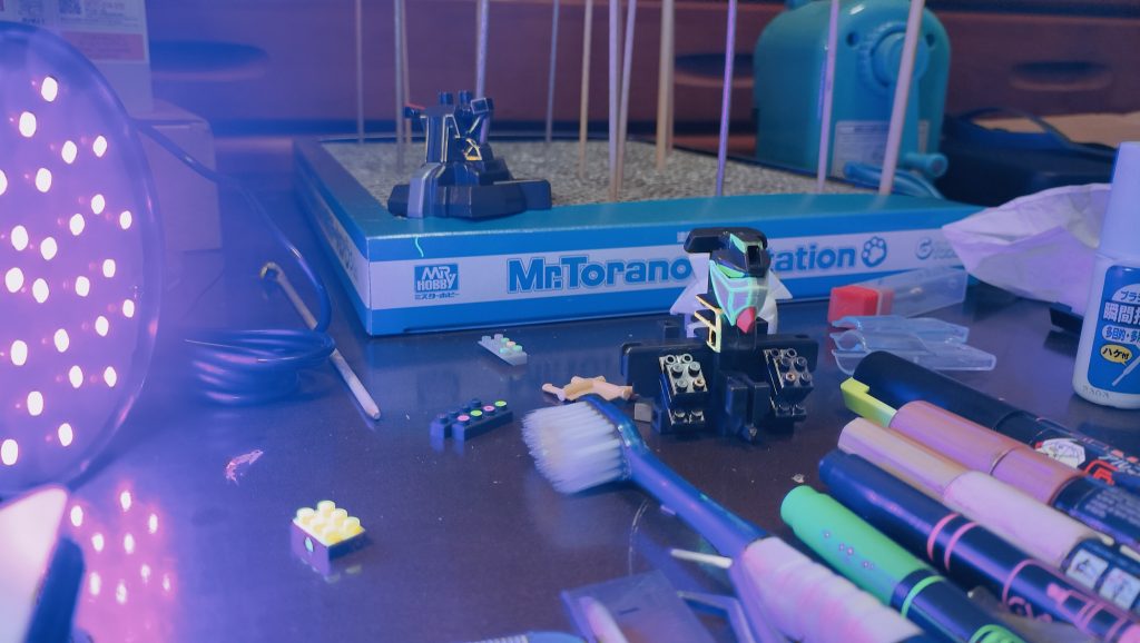 驚くことにこの技法はダイソーの5本で100円水性蛍光マーカーセットで、ヌリヌリしてます。簡単そうに見えて、プラモ用塗料とは別の苦労がありました。トップコートで保護しないと、当然すぐに擦れ落ちるわけです。★他の蛍光マーカー(ガンマカや、油性マーカー)は塗膜も強く隠蔽力も強いのですが、水性マーカーの良いところはブラックライト当てていないと半透明と言ってよいほどなのでもとの色を邪魔しにくく、ブラックライト当てたときだけ盛大に光るので、そのギャップの演出に一役買います。また半透明の利点として、ラピーテープやホログラムテープの上からヌリヌリすると、通常光では反射で光り、ブラックライトでは蛍光が光るという2度美味しい使い方ができるのも良きかな。