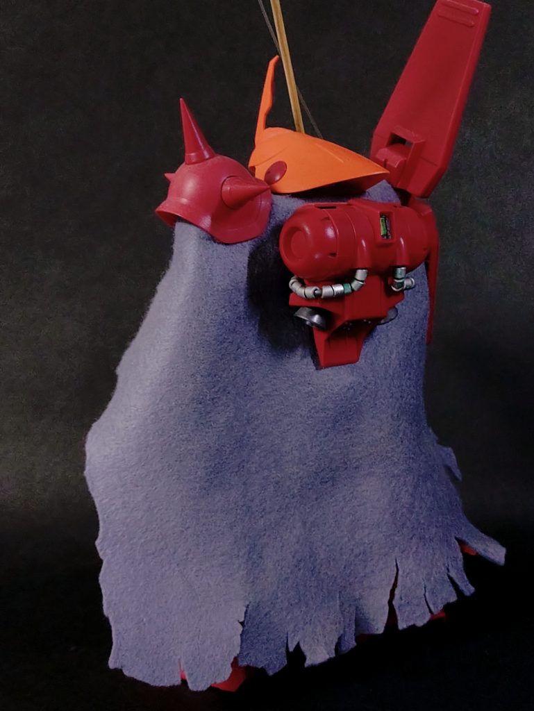 本体のMGマラサイは表面処理を丹念に行い、成形色より少し暗めに全塗装。武器は「昔、棄てちまったな」とのことなので持っていません。代わりに愛用の釣り竿とマントを制作。竹ひごに実物のテグスを接着しただけてすが、スケール的にかなり太いのでどんな大物でも大丈夫ですf(^_^;)マントは百均の手芸コーナーで購入したフェルトをボロっちく見えるように適当にカットしています。バックパックはマントの外に出るように接続部に穴を開け、肩アーマーや首の間にマントを挟み込んで固定します。