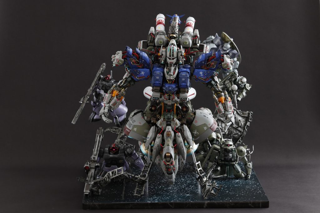 MGサイズをベースに製作したのですが、結果PGサイズくらいになってしまったで、配置は順を追って真ん中にMG、後方はHGで遠近法を表現してみました。 できるだけ空いた空間を埋めるために軽いHGにはデブリを使って浮いてもらってます。