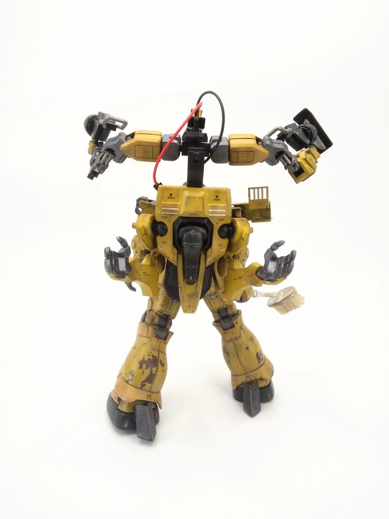 第一線での戦闘運用が厳しくなった旧型ザクを整備用に転用(半ば私物化)し、本人曰く “あっちの谷で拾った” やら “そこら辺に転がってたヤツ” という謎のパーツや廃棄部品を使ってあれやこれやと改造している。そのシルエットはもはやMSと呼んでいいのかすら怪しいが、１機で多様な作業に対応できるようによく考えられたもので、突飛な独創性と生真面目な職人哲学が同居している。