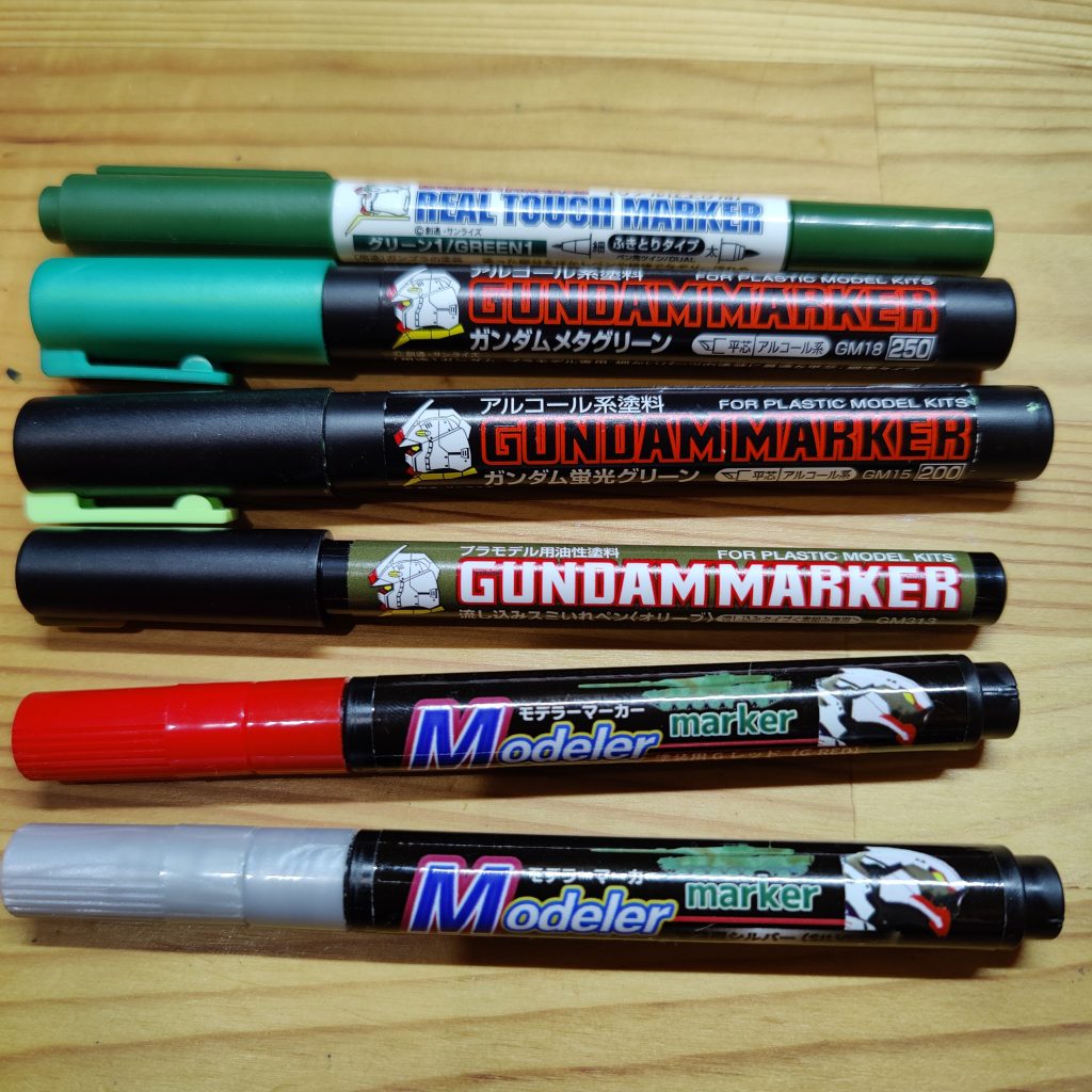 使用したマーカーです。リアルタッチマーカー(グリーン1)、ガンダムマーカー(メタグリーン)、ガンダムマーカー(蛍光グリーン)、墨入れペン(オリーブ)と、100円マーカー(レッドとシルバー)。赤と銀は、ガンダムマーカーより100円マーカーのほうが隠蔽力が高くてお気に入りです。あと光沢トップコートを丸1本吹いています。