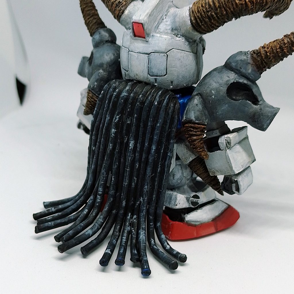 髪メイン画像のガンドランダーのキャラクターは、ガンプラのフレームをジッポで熱しながら一つ一つS字カーブを描いて造形しています。 はんだごてを使って溶かして、ガンダムのバックパックに貼り付けます。