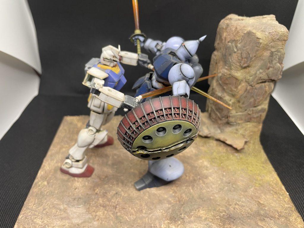 ジオラマベースは百均の木製トレーを裏返して使用。スタイロフォームで崖部分を貼り、木工用ボンドで百均のウッドチップをペタペタ貼って、隙間や地面は石粉粘土で埋め。同じく百均のアクリル絵の具で塗装しました。