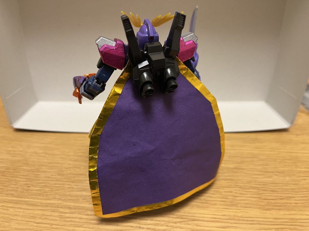 ゴッズレイウォール背部に追加された専用マント。「ガンダムからの攻撃のみ」を超圧縮して、ダメージを完璧に無効化しつつ衝撃も受け流す特殊エネルギーフィールドを常時形成する特殊能力を有している。対ガンダム戦におけるその防御力は、もはや強靭を通り越して、正に言葉通り「完璧」と言っても過言ではなく、ツインサテライトキャノン、挙句はガンダムが行ったものであればコロニー落としですら、ノーガードで防ぎ切るほど。しかも、装着したMS全体(コックピットがある胸部・頭部・腕足、さらにはフレームや間接部など)に付与する為、わざわざマントで覆って防ぐような動作も不要で、間接部やフレームを狙った攻撃も通用しない。圧縮率は99.99999%であり、ダメージこそ完璧に無効化されるものの、残り0.0001%の僅かな衝撃は受ける為、ある程度は吹き飛ばされるノックバックが少なからず存在するが、本機の場合はゾンビシステムによるダメージ軽減も完備されているので、その僅かな衝撃ですら抑え込む。
