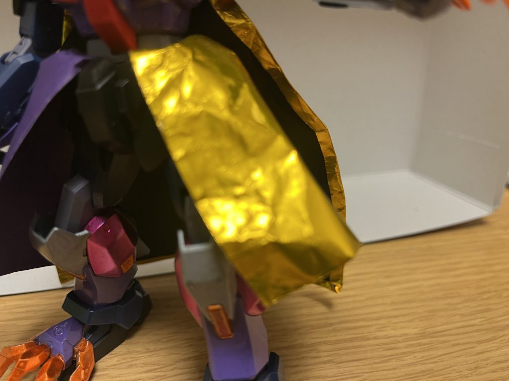 ゴッズムレータ左腰に追加された専用ローブ。アルティメット細胞の力によって、「ガンダムからの特殊能力」のみを防ぐ特殊耐性を本機に付与する。対ガンダム戦限定かつ完璧とまでは言わないものの、この特殊能力耐性も優れており、物体を分解・霧散・消滅させる超破壊能力、生命活動の停止と世界をも破壊可能な必殺技、ブラックホールによる特殊攻撃など、攻撃に関わるものであれば殆どを防ぎ切る。この耐性の数少ない弱点は、超分析能力による特殊能力の無効化と、時間操作による対ガンダム特攻の消失のみ。前者は無効化精度の高さが成せるもので、後者は本機を対ガンダム特攻が存在しない時間まで逆行させる事で本形態を封じるというもの。