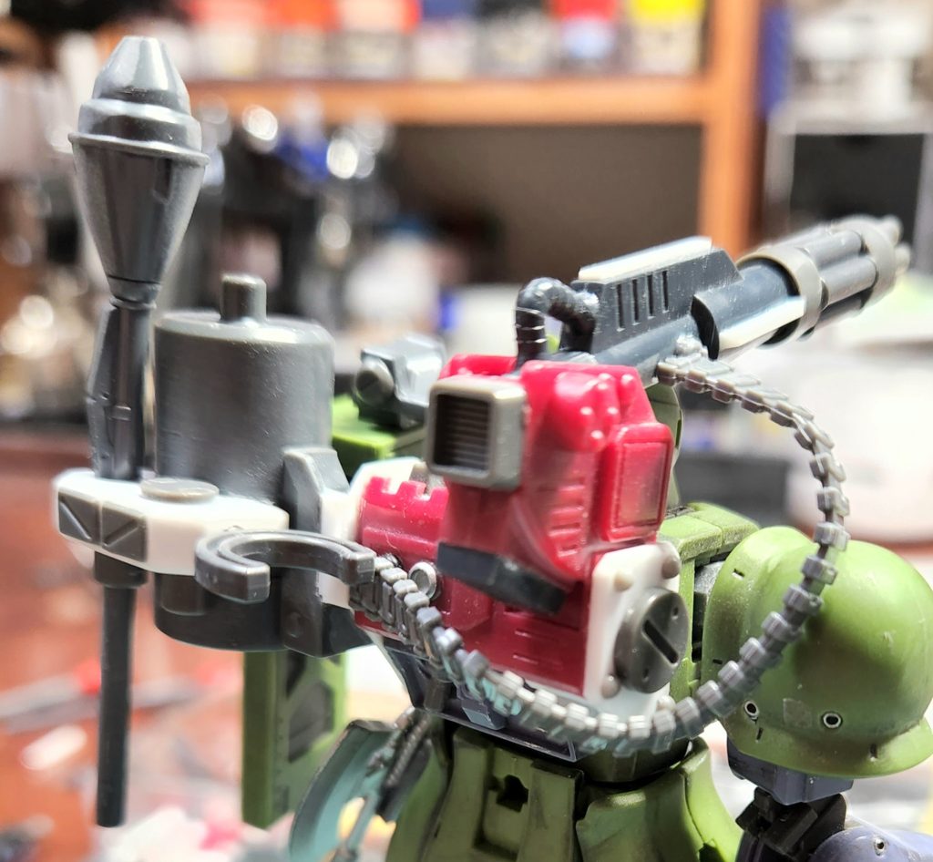 ①サイドの隙間がある所をプラ板で埋めてちょいとディテール追加。②キャノン砲がイマイチなので切り落としてガトリングへ変更。③給弾ベルトがあった方がカッコ良いのでザクハーフキャノンから拝借。④グフカスタムで余った弾倉をバックパックに取り付け。⑤弾倉背負うだけじゃ勿体ないので弾倉にプラ板で自作したウェポンラックを取り付け。今回のザクIはバックパック改造一点豪華主義ですww