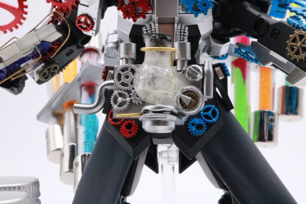 Bi-ドライバー(バイドライバー)ビルドドライバーを元に制作されたエネルギータンクから供給されたネビュラガス、バグスターウィルス、ヘルヘイム、コズミックエナジー、コアメダルの力をガンプラに循環、供給させるネオカイザーシステムシステムの要。ハンドルを回すことで必殺技を発動する。エネルギーをフラスコ内で煮詰めて更に凝縮することで出力を上げている。