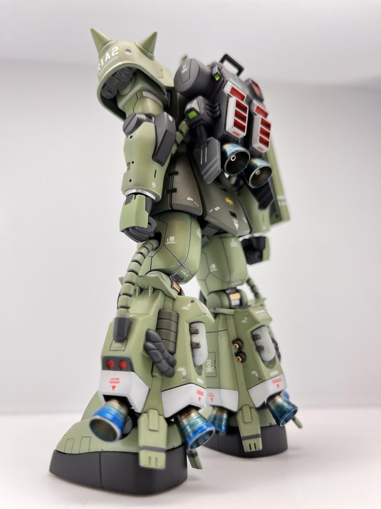 左後方より(*´ω`*) 以上が本機のデータであります。R1タイプが少数生産だったためか、消耗品や、予備品の使用が少なく、結構な在庫があります。本機により行き先の無かった脚部とバックパックが有用に活用できるかと。型式はMS-06R1A2を予定しており、正式採用の後には脚部等を更に増産し……(^○^) ふむ、良くわかった。共通コックピットと、OSはどうだった？(*´ω`*) は、どちらも非常良く出来ています。ツィマッド社のMSは未経験なので比較はできませんが、ジオニック系のコックピットに比べると若干スラスターや推進系の操作が難しく感じます。特に最高速度を出そうとすると安全装置（これはヅダのせいなのを知らない）が作動します。現行のザクに乗り慣れている連中は少々難儀するかもしれませんね。(^○^)そうかツィマッドのと比較か…。(*´ω`*) なにか？(^○^)いや、何でもない。とりあえず正式採用はしない方針だ。(*´ω`*)え？本機は統合整備計画に則って…。(^○^)確かジオニックでは06Rの改良型（後の06R2）を試作しているのを聞き及んでいる。そちらに注力してもらいたい。更に言えば、そろそろ次期主力MSの開発が急務となっている。(*´ω`*) ということは？(^○^) 正式採用、型式の付与はなし！ただしストックしている06R初期型パーツのF2への換装は認める。以上！！ブッ…。（通信の切れる音）(^○^) ………。とりあえずF2への換装は認めてもらったし、一歩前進？ 