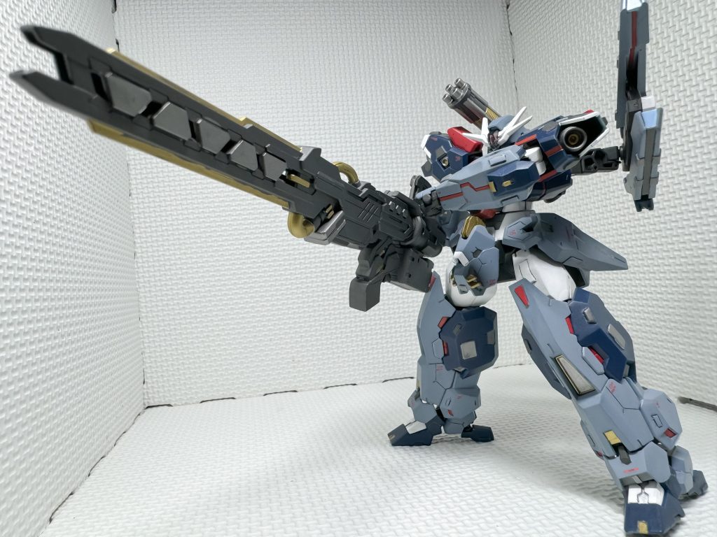 メインの兵装の「大型ビームキャノン ティタノマキヤ」です。大型の艦船や、拠点を遠方から狙撃する武器になります。肩などの機体各所の赤色のパーツは、仮想シェルユニットで、本機の運用のために高いパーメットスコアを要することから、人間の代替として、外付けの演算ユニットとして機能します。狙撃時の補正などをする際に使用します。砲身は、元のガトリングの基部を使って接続できるようにしています。SDのサージェントヴェルデバスターの武装を少し、整形と塗り分けをして、本体と馴染むようにしました。