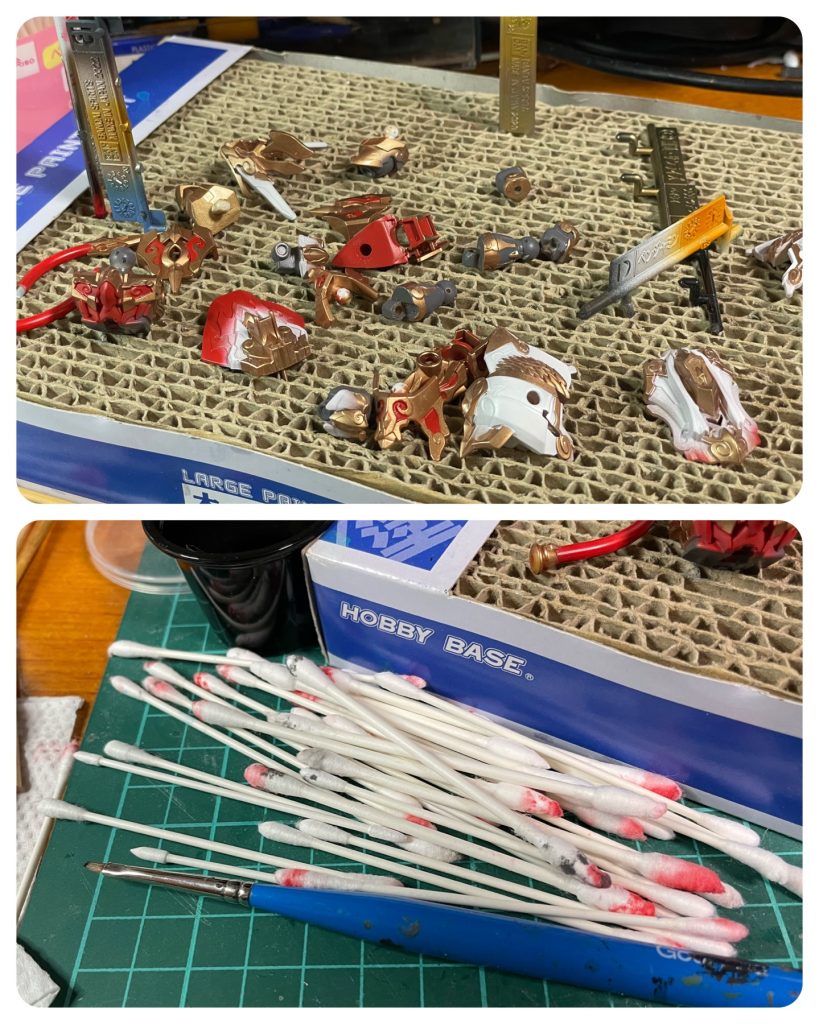 塗装工程金: Mr. Color スーパージュラルミン+色の源イエロー、マゼンタ白: 水性ホワイトサーフェイサー1000赤: 水性ホビーカラーガンダムレッドグレー: 水性ホビーカラー エアリアルグレー青: 水性ホビーカラーガンダムブルーピンク: 水性ホビーカラーガンダムレッド+水性ホワイトサーフェイサー1000オレンジ(エフェクトパーツのグラデーション): 水性ホビーカラーイエローオレンジ+色の源マゼンタ他一部、水性ホビーカラーフラットブラック、 ファントムグレー今回はノーマスキングで塗装しました。最初にエアブラシでラッカーの金を塗り、その後パーツごとに白、赤、グレーのどれかをなるべく金部分を残すようにエアブラシで細吹きし、はみ出しをマジックリンで落として拭き取りました。その後残りの箇所や拭き取り過ぎてしまった箇所を筆塗りしました。細かい箇所を拭き取るときは、マジックリンを筆で塗って塗膜を溶かし、乾いた綿棒で拭き取ると良いです。赤の筆塗りは最初はシタデルカラーのメフィストンレッドを使ってたのですが、ガンダムレッドに比べて暗過ぎたので、結局ガンダムレッドで塗り直しました。