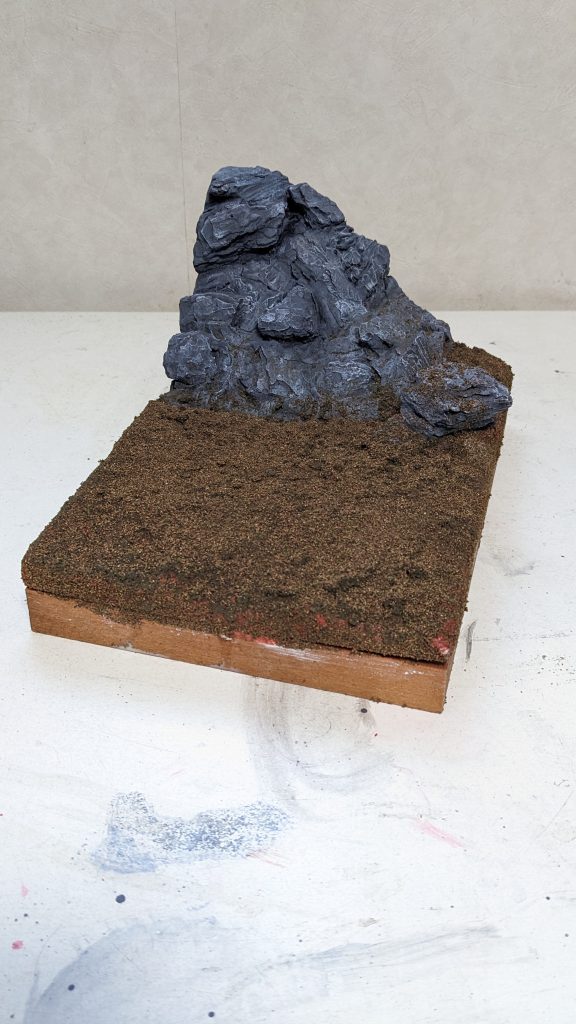 グレーで塗装。隙間を黒で影を付け白でドライブラシでササッとしてこんな感じ。更に鉄道模型等で使うナノプラッツ等で地面を作り土台はほぼ完成。この後、配置してみたら寂しいので岩や草を追加しました。