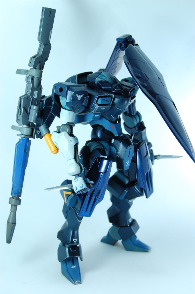 隊長機はスナイパーライフル装備でファラクト不在時に代替する役割を担う。簡易的な消火剤を付けた白い腕と片翼で独自の美学がある装備。くちばし状のビークマスクは僚機間で空間情報を共有するようなモードのイメージです。首が埋まってて顔面をいじりづらいザウォートでも、大きく顔の印象を変えられた気がします。 差し色部分はミスタカラーのミディアムブルー、フレームなどは成型色とタミヤカラーの舞鶴海軍工廠グレイで、シェードブルーでウォッシングして艶消しコート。メインカラーはディープオーシャンブルーにこちらもウォッシング。さらに雨で濡れてにじんだりムラが出てる感じを出すためにパーツの合わせ目方面などからプリズムブルーブラックをグラデーションっぽく吹きました。プリズムブラック部分はクリアコート、他は半光沢にして光沢感もグラデに。カラスの羽の構造色や雨で濡れて深く黒ずんだ濡羽色っぽさを出すことを目指しました。肉眼ではそこまで効果はわかりませんでしたが、ライティングしたらけっこう化けた印象です。プリズムブラックは濡れ表現とも相性よさそうな感じがしますね。ウェザリングはシルバーでドライブラシを少しと足回りを汚した程度です。