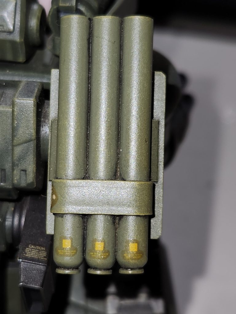 三本のランチャーをまとめるバンド状のパーツはホームセンターに売っている『板はんだ』を使用、下のフタのようなパーツは使いきった100円ライターから取り出した部品を使ってます。 