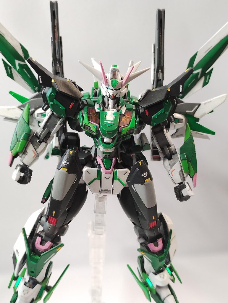 ◆デザインについて:例年通り、「新シーズンのFC岐阜ユニフォーム」をイメージしてミキシング&塗装案を組んでいます。FC岐阜の2024年ユニフォームは↓の通りで、https://x.com/fcgifuDREAM/status/1733420585072677364?s=20https://www.fc-gifu.com/news_information/122080.html特徴としては・襟なし・袖とパンツが黒色・鵜飼の手縄をモチーフにしたラインが入っているといったところで、デザインに盛り込ませていただきました。手縄モチーフのライン再現は僕のアイデアではなんともならず、「結った縄」に見えるデカールを肩や頭部に貼っています。FC岐阜のマスコットがピンク色で、かつ2024シーズンのボールもピンク色ということで、各所の差し色としてピンクを使っています。ベースキットの「エアリアル改修型」が悪役チックな顔付きだったので、そこから「鬼」をイメージして改造を進めましたが、背中の複合兵装付けたら「頑駄無大将軍」って印象が強くなりすぎちゃいましたね……。(余談ですが、ベースのエアリアル改修型から、都合4-5回アンテナ折れました…… 決闘で負けた呪いですかね???)◆制作について:相変わらず大好きな「新MAX塗り」、更に今回は筆塗りで仕上げていきました。特に白色で仕上げる箇所は情報量増えてとても良いのですが、僕の腕のなさからモールドをかなり埋めてしまいました……。特に頭使わず毎日ちょっとずつ進めていける筆塗り、楽しく進められますが、改善ポイントです……。ナックルガードは百均のネオジム磁石で腕と接続する仕組みにしました。武装に干渉しても問題にならない一方、大きく腕部を加工したことで手首の保持力がガタ落ち。結果的に、重めの武装を持たせたい仕上がりになってしまったため、なかなかままならない仕上げになってしまったかもしれません。ディティールアップに、30MMの3Dメタリックシールを多用しました。これいいですね! 手放せなくなりそうです!