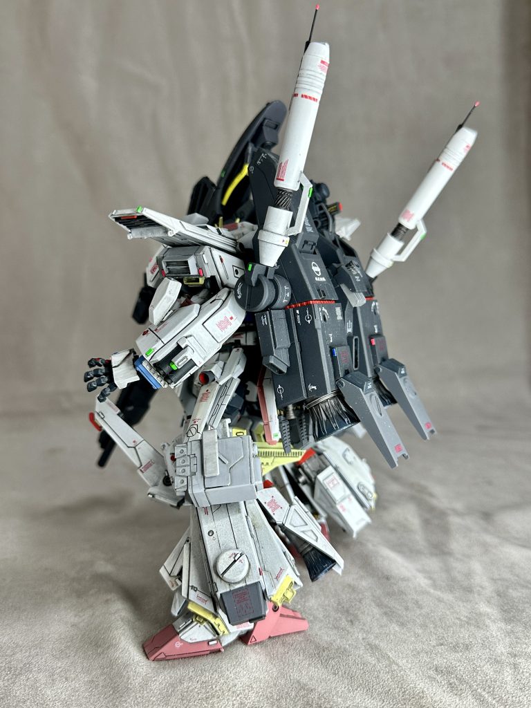 　左腕には中～近接用２連ビームカノンを装備。肘部分には大容量のＥパックを装着。メインプロセッサから独立した自律型エイミング機構が導入されており、左腕の可動範囲内全域に自動制御によるビーム弾幕の展開が可能。　背部バックパックに装備されているビームサーベルは、ビームカノン機能を廃したかわりに形成ビーム刃の出力を上げた斬撃専用のタイプに変更。この巨大ビームサーベルは基部で回転し、AMBAC機動システムにも寄与している。