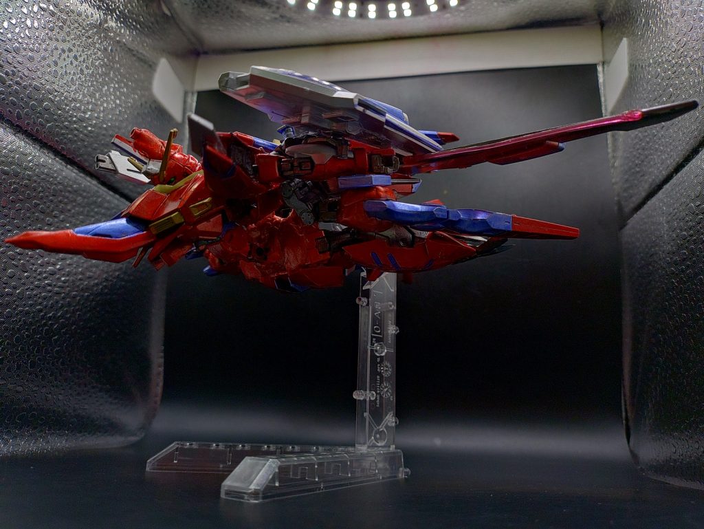 ◯アクション見た目を意識して、ライフルとシールドのマウント位置を変更しました。イモータルジャスティスと異なり、薄くスマートなシルエットに仕上げました。シールドは機体下部にマウントする案もありましたが、シールドが紛失しても飛行できるようにと、変形プロセスの削減のために、腕に装備したままにしました。