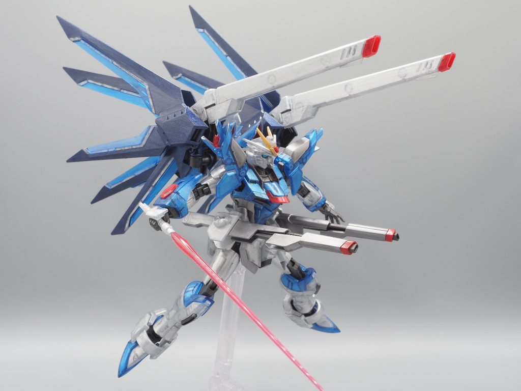 クリアパーツの内側はアクリジョンシルバーで筆塗り(4回くらい)しています。外側は、クリアブルー部分はメタリックブルーとシルバーを1:1で混ぜたもので、クリアホワイト部分はシルバーをそのまま、1回だけ塗っています。クリアレッド部分はメタリックレッドです。差し色になるので、しっかり塗りました。非クリアパーツは、シルバー部分は赤鉄色とシルバーを1:1で混ぜたもので、パープル部分(バックパックのウイング)はメタリックブルーとメタリックレッドを1:1で混ぜたもので塗っています。ウイングは筆塗りの方向を一定にして、筆ムラがグラファイト加工っぽく見えるようにしました。フレーム部分(黒色のパーツ)は赤鉄色で塗っています。