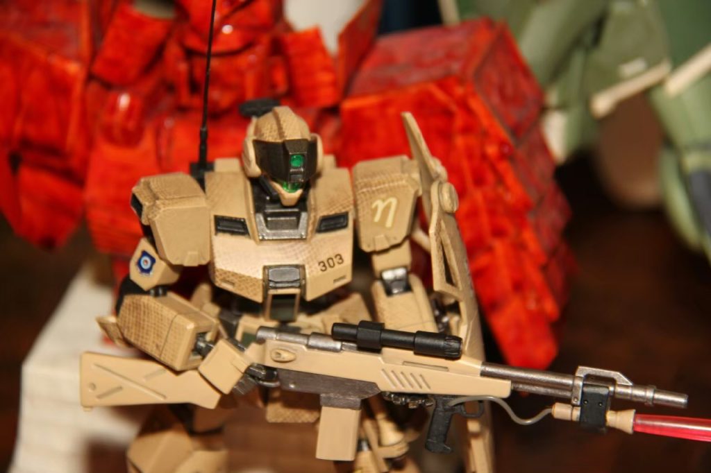 スコープはレンズから映像としてコックピットに送られる、という設定の上であえて接眼レンズは取り付けておりません。マガジン差し込み口はウェーブのダクト、マガジンはプラ板積層で削り出し、ビームサーベルのマウントは５ミリ角のプラ棒から削り出し、コードは壊れた電化製品の基板から拾ってきたものです。ライフル前部のグリップは別のキットの物を流用、トリガーがビームライフルのスイッチになっているという設定の元、トリガーもそのまま残しました。