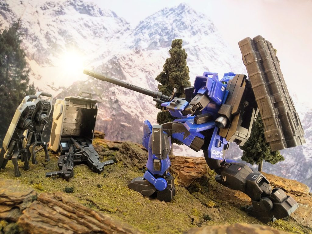 一射、二射、三射。弾速が遅く、放物線弾道なので決して扱いやすいとは言えないが、戦車砲以上の口径をMSの機動力で運用できる事は今後の戦術を広げるだろう。…と言いたいところだが、ジオンの新型は300mmを超えるバズーカをホバー移動で流れるように撃つ。その半分程度の威力の砲を分解して箱に詰めて運んでなどと…オマケにこうも反動が大きいと移動しながらの射撃は不能。なのにサイレンサーも無し。…ダメだなコレは…最低ノルマの回数はこなしたからもういいだろう…そう思ってマシンガンに持ち替えようとした時、ブルーの頭上スレスレを轟音が切り裂いた。…!!!? 撃たれた!?こちらの方が高所なのに、不利な低地から同じ距離をカウンター狙撃だと…!?