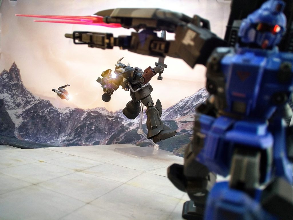 メインカメラを落とせば自由に動けまい。武人として正面から闘ってみたい気持ちはあるが、腕のある乗り手ならいずれまた相見える事もあるだろう。 ~ ~ ~ ~ ~ ~ ~ ~ ~長編ブンドド、最後までお付き合い頂きありがとうございますw前回のBD1は旧キット(HGUC 080)、今回は新キット(HGUC 207)です。どちらも同じ友人からの制作依頼で、旧はシンプルに、新は陸ガンとのMixということでオーダーを頂きました。オプション注文は “輝き撃ち” 、しかも “立ち輝き” 。…ムチャクチャゆーてくれるわコイツwと思いながらも、そうやってヤイノヤイノ面白半分に注文つけてハードル上げてくれるお陰でこちらの技術力も上がるというもの。加工箇所に関しては「制作記録」の方をご覧ください。隠し立てせず公開しておりますw シンプルな白背景で撮影した写真も「制作記録」に一部纏めました。二丁マシンガンのスタイルは、映画『リベリオン』の≪GUN=KATA≫をオマージュ。これも依頼主からのオーダー。幾つかのカットはまんまその構図で撮っていますw 背中のランチャーと2連ビームは私のアドリブ。評価試験隊という設定を掘り下げ、ランチャーはサイサリスのMLRS、2連ビームはジム・ストライカー、180キャノンへのダメ出しはジムスナイパーと、後の連邦機へ繋がる流れを意識しました。依頼主も「かつてないカッコ良さ!フルアームドへの試行のハズが超えとる。全体のバランス、塊感が凄い。依頼した構想以上の仕上がり!」と大満足頂きました。( ゚д゚)ドヤァ!←せっせと作っていた基地ジオラマと崖上ジオラマはこの新BDの為です。故に、ある意味、今作は仕込み期間3ヶ月の大作? 背景壁紙も年末くらいには用意してました。ユウがBD1に乗っていたのは11月末~12月15日(キャリフォルニア攻防戦 BD1vsイフリート改)迄の北米。北の方なら雪有るよね、と。 一連のシーンは照明を工夫して夜明けの表現にチャレンジ。ライバル機として登場させたグフカスタム。ボスキャラを用意してブンドドシーンを撮りたいと、納品前日に思い立って8時間でデッチ上げた突貫工事w 納品2時間前まで撮影していたというw ディティール一切無しでダッセェのでいずれ改めてちゃんとリビルドしたい。パイロットのキャラ設定も考えてあるので追々…