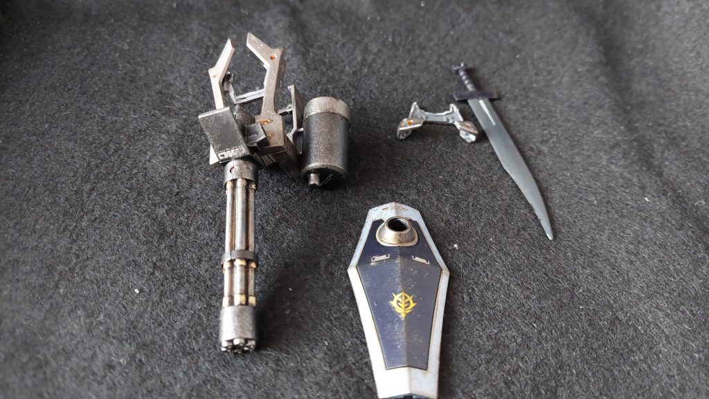この機体の武装面で一番目を引くのはやはりガトリングシールド。焼鉄色、ゴールド、メタルブラックの3色で塗り分けました。こちらに収納するヒート・サーベルの刀身のみ剥げ防止で中央以外は成型色ですが、デザインナイフで削るなどしてできるだけ鋭利になるようにしました。