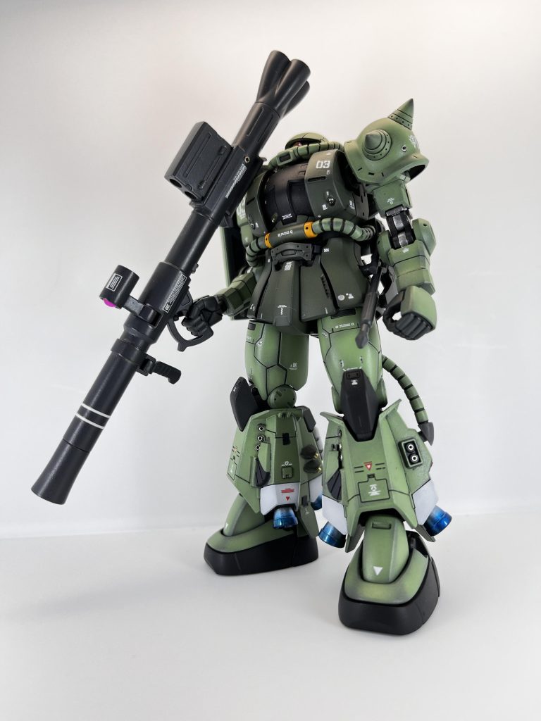 左前方よりザクバズーカを担いで。脚部のディテールはHGUCのものより造形が細かいので、マスキングで塗り分け、開口していそうな部分は穴を開け、メタルパーツを何種類かねじ込んでディテールアップ。バーニアも青焼け風に塗装しました。