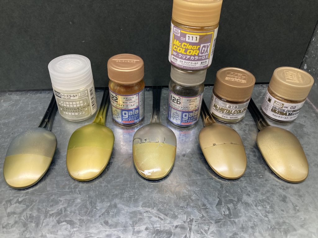 黒下地に左からトパーズゴールド、スターブライトブラス(写真ではスターブライトゴールドとなってますが、撮影時に置き間違いしました…)スターブライトシャンパンゴールド、ミスターメタルカラーのブラス、ウルトラメタルカラーのウルトラゴールドに下半分はクリアゴールドを吹き重ねたものです。私の中の百式に1番近い色として、左から2番目を選びました!