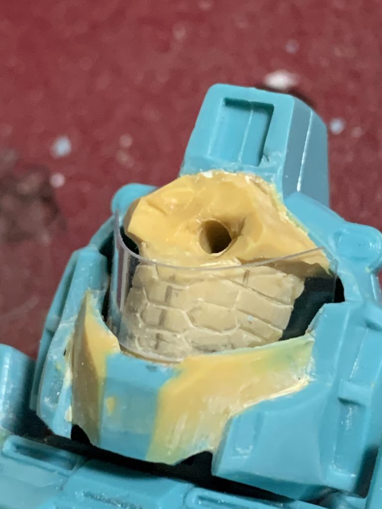 頭部の真ん中に合わせ目が出る構造だったので、思い切って構成の変更を行いました。おでこパーツをアトハメするパターンに変更しました。クリアバイザー越しの内部メカをMGデザインを参考に造形しています。