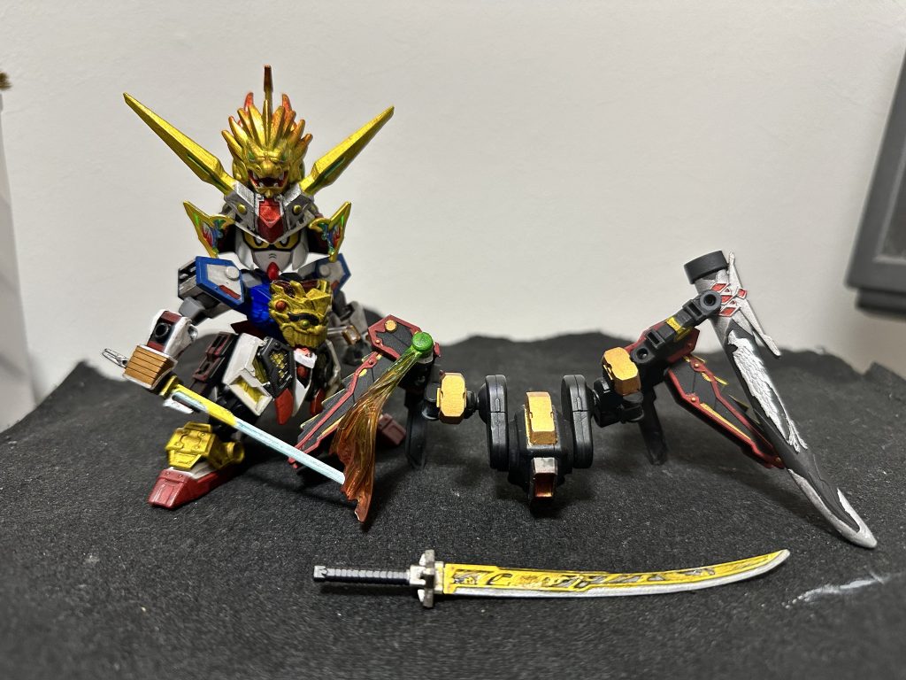 駄舞留精太から代々続くからくり一門の一人、“二華”の手によって作られた機動鎧「御羅装留(ミラソウル)」機械仕掛けのため武者頑駄無の鎧ほどの堅牢さはないが、スラスターを内蔵しており、農丸の多彩な動きを補助できるようになっている右肩部には大太刀「武久丸(むくまる)」を収納する鞘が接続されている武久丸はまたの名を「武輝丸影打ち」と呼ばれ、輝羅鋼で武輝丸を打つ前に作られた試刀である……とか、そういう脳内設定です。鎧のベースは78代目と劣化武者頑駄無と水星の魔女のミラソウル社製フライトユニットを切り貼りしたりビルダーズパーツのジョイントで繋いだり、ですね吹き返しの輝羅鋼は隠密エアリアルの胸パーツのものを使っています、結構違和感ないですよねw御羅装留を外すと若農丸っぽい配色になるのがちょっとお気に入りなお、農丸頑駄無では眼帯をつけていません……公で眼帯つけるようになったのは副将軍に出世してからなので、ね