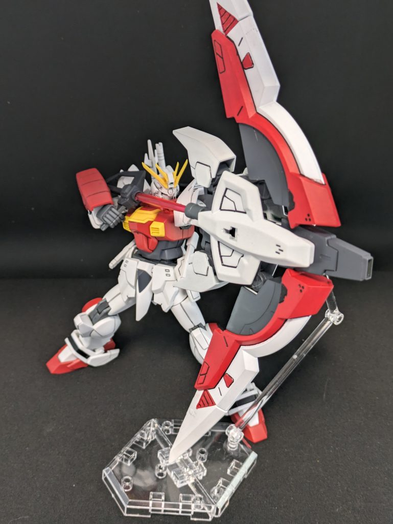 確殺!ブレイズシュート!射撃武器あるじゃねえか!!ライジングガンダムといえばライジングアロー。ライジングアローといえば他に例を見ないほどのレア武器。ライジングガンダム以外で弓を使うガンダムはたぶんいないはずです。しらんけど。ライジングガンダム要素を取り入れるためには外せない弓を、ビームボウまるまる移植する以外でどう表現したものか・・・と悩んだ結果、量産型ジオニックソードがいいんじゃないか、と気づきまして。ジオニック感を薄めるべく一部意匠を除去し、色を塗ってそんな感じに見えないように努めてみたんですが・・・やはり白は大変です。何度重ねて塗ったことか。一筋縄ではいきませんね。弦は省き、矢を引いた格好になるようにグリップ部分を持たせ、間をビールサーベルのビームで繋いでそれっぽくしてみました。 反対側、つまり左手にはメルクワンの銃を持たせています。何故なら元のジオニックソードがでかすぎて片手では保持できずウェポンディスプレイベースを使うことになってるんだけどそれを接続する手段が「左手で持てるもので」「3mmピンでジオニックソードに接続できて」「ディスプレイベース側にもピンで接続できる」の3条件でしたのでそれが揃うのがたまたまメルクワンの銃だった・・・というわけです。ね。