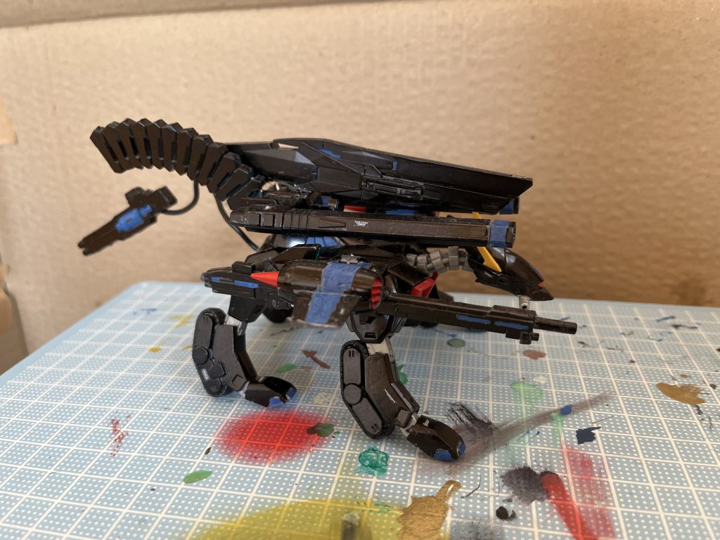 横から。バクゥ本体の右ウイングには、リゼル系統のビームライフルが強引に接着されており、新規に付けられた照準器により精密射撃を得意とする。元々搭載されていた二連装レールガンの上にはダブルオースカイのロングライフルを装備。エネルギー消費が大きいためか、ビームマグナムのカートリッジが接続されている。尻尾に当たる部分にはガンダムキュリオスのGNビームサブマシンガンをケーブルによって装備。フレキシブルに動くケーブルのおかげで背後や正面など様々な位置に高速連射する事ができる。