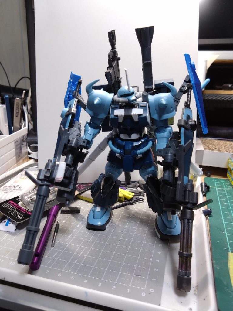 対艦ライフルも装備予定でしたが固定場所とグフカスタムの戦闘イメージが違うなとコレもやめました。今回は自分の好きなグフカスタム。シャアズゴック制作時に近くにあったジャンク購入のグフカカスタム。これに私の好きな高機動型ザクの脚着けたらカッコイイ✕カッコイイでめちゃくちゃ良いのでは？という思いつきで家の過去作品のザク脚を着けたらカッコイイ！というところから始まりました。しかし過去作品とはいえ部品取りにするには勿体ないなぁと某オークション観ても割高でパーツも中々無い。うーむと考えながらパーツが揃ってからいつかやろうと思っていたら、買い物に出かけたときに中古ショップでジャンク完成品を発見！それで制作始める事ができました。腿の部分は初め妥協してましたが、どうしてもグフらしい腿にしたくてグフカスタムの腿の内部を削って中に入れました。3連ガトリングのバレル穴あけ加工は手元にあったプラパイプに網戸用補修テープを貼り付けて1mmピンバイスで同じ間隔で下穴開けてから2mm位かな？で広げてます。網戸テープは使用後の粘着が面倒でしたが等間隔に穴開け加工するには良いですね。最初の写真のように無塗装状態でもそこそこにカッコイイのでグフカスタムのカラーをベースに考えていましたがブラックサフがここまでハマるとは思いませんでした。一度違うカラーをやりましたがつや消しブラックが忘れられなくて今のカラーにしました。それと黒い三連星っぽくならないように注意しました。ディティールもかなり頑張ってみましたがつや消しブラックだとあまり見えないかもですね。ボリューム多くて写真撮影が苦労しましたがなんとか。上手く皆さんに伝わればよいですが。エース機なので大佐の階級マークにしておきました。宇宙に上がったグフカスタムが高機動型ザクの余剰パーツを駆使してカスタマイズしたエース機…というような妄想設定。100均のガードレールの支柱もプロペラントタンクになりました。ココは普通のクリアー吹いたのですが解りにくいですね。頑張って制作したので見てやって下さい。🙇