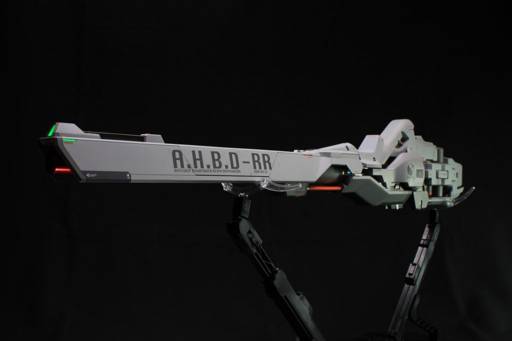 ※IF設定注意武器名A(AntiShip)H(HighPower)B(Beam)D(dominator)-RR(ロッドライフル)アンチシップ・ハイパワー・ビーム・ドミネーター・ロッドライフル。学園への大規模なテロ攻撃の後、地球寮の生徒により本機を含めた複数の設計図が発見され、株式会社ガンダムの兵器部門により、有り合わせのパーツで建造された対艦級ビーム兵器。設計図の出所は謎に包まれており、各所にアドステラ期の兵器には見られない異様な技術が採用され、その性能を設計図通り完全に再現することは不可能とも言われた。ビームの出力方法が未知であり、ガンド技術由来の出力方法に変換させた上で、戦艦への搭載を想定し建造されたものの、クワイエットゼロへのキャリバーン出撃に伴い急ピッチでモビルスーツに携行できるよう調整が行われた。パイロットの命を一切担保しない、ガンドアームの性能限界を追求したキャリバーン。そしてその鎖の外れた化け物を駆る水星から来た魔女。AHBDは略称をアバダとも発音できる事から、古の伝承からの禁忌の魔術に準え、アバダケダブラーと呼ばれるようになった。禁忌たる理由はその性能にあり、AHBD単体での高出力射撃で、直撃した戦艦を一撃で撃沈するほか、パーメットスコアの上限値が解放された本機を携行しているキャリバーンとの組み合わせで、ビーム弾が傍を通過しただけでも射線上に莫大な被害をもたらすことを可能とした、まさに魔女の呪いとも恐れられる性能を誇った。しかし、携行するためにはキャリバーン本体のスラスターとクアドラスラスターを搭載したヴァリアブルロッドライフル1本のみでは射撃の際の衝撃をカバーする推力を補いきれないため、キャリバーンを巨大外殻ユニットへ接続する必要があった。そして、その巨大外殻ユニットの設計図もまた、発見されたもの中に含まれていたのであった。