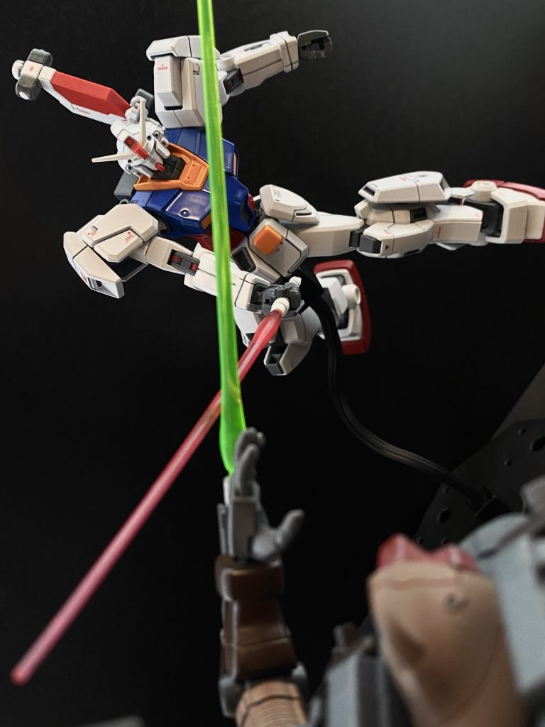 光、光が入ってくる。私の中に。その光は身体中にコードや管が繋がれた少女の姿になる。その少女は、助けを求めるように両の手を差し出して…。そして私は聞いてしまう。「おまえっ!…お前が父さんを…っ!」 女の子!組み合った機体を通して、ドムのパイロットの声が聞こえたのだ。まだ幼なさの残るパイロットの叫びは、私に一つの事実を知らしめす。…そうか、私が命を奪ったあのパイロットは、彼女の…。 機体に、自分に強い衝撃。その振動に我にかえる。一瞬動きが止まっていた、ドムの放ったミサイルが左腕に直撃したのだ。すぐさま機体を立て直そうと操縦桿を倒す。が、動揺した私の、ガンダムの動きは鈍く…。モニターの中の光景は、ガンダムの右腕を弾きながら、ドムの左腕がボディブローのようにその胴に突き刺さる様がまるでスローモーションのように見えて…。 衝撃。コクピットを包むシェルユニットが、フレームが悲鳴を上げ、MSの腕部という質量体がぶつかる衝撃は、ヘルメットのバイザーを砕き。モニターを割る。頑丈なはずのコクピットをひしゃげさせながら、私に巨大な質量が迫るのがわかる。そしてその質量は瞬く熱い光を放ち…。 …空を見た。…どこまでも青い、蒼い、空を見た。