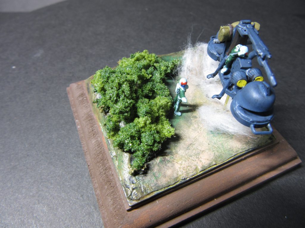 上方より。ベースはホームセンターで購入した台座。茶色に色を塗りました。台座の上にプラ板を合わせて切り出し、その上に木粉粘土で地形らしきものを成型。塗装しました。茂みは鉄道模型から。