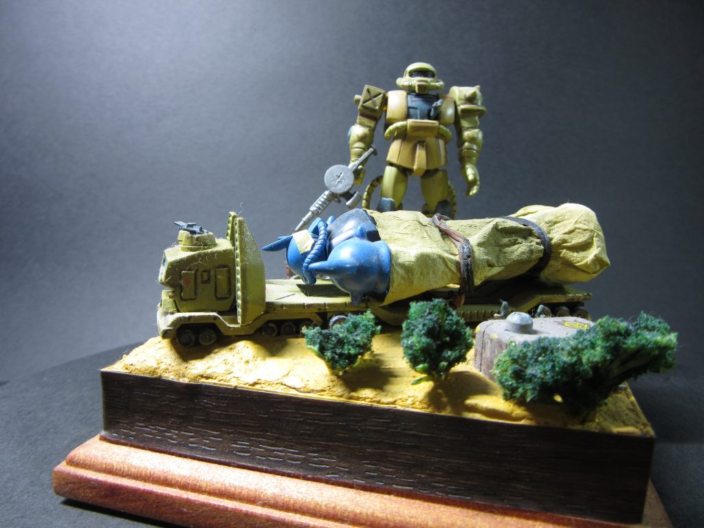 制作イメージは砂漠にあるジオン軍の駐屯地に新品のグフが補充された的な感じです。グフはブルーの設定画のカラーとし、量産型ザクはデザートカラーにしてみました。