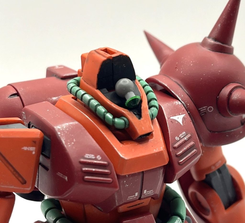 モノアイの改造はかなり楽ちんで、キットのモノアイを貼る黒いパーツを外し、空いたスペースに軸を差して固定し、その軸で回転出来るもう一つの軸を挿し、その先端にモノアイを貼り付けるだけです。モノアイは緑色のジュエルシールを使いました。ヘルメットは内部の突起が頭頂部に刺さっているだけなので、簡単に外せてモノアイを左右約180度回転可能です。ユーザーに改造してもらうのを前提とした設計なのかなと勘ぐってしまうくらい、改造に適した構造だと思います。改造では簡単に実現できても、それを誰でも組み立てられて誤飲や紛失、破損、あとはコストの問題をクリアしたインジェクションキットを量産化するとなると一気にハードルが上がる場合は多々あると想像しています。そこで敢えて改造しやすいようにしてあるのかな、という構造的な意図を感じるキットはたまにあります。