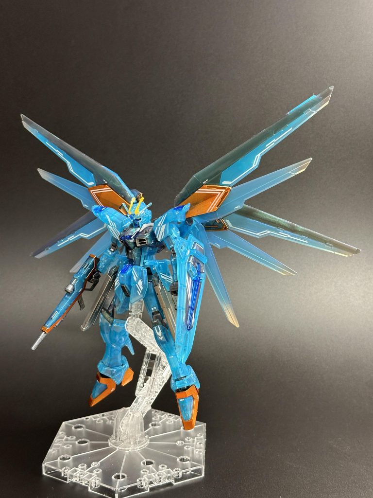 コンテストは参加者全員が同一キットを使用、しかも成形色を生かす必要がある(全塗装もルール上は可能ですが、それだと意味ないので)、というかなり特殊な条件。とりあえず他の方の作品と差を出さないといけないと思い、いろいろ考えました。最終的には特徴的な成形色をより引き立てるような方向性としました。・差し色としてメタリックオレンジをキャンディ塗装(もちろん西川さんのイメージ)。元キットは全身が青いので、差し色でメリハリを出す狙いで・羽の先端にシルバーをグラデーション塗装。初挑戦でしたが意外と簡単にできますね・全身にデカールを貼り付け。レギュレーション順守のため、バンダイ製デカールのみ(主にRGインパルス用とHGユニコーン用)を使用。これが結構大変でした！・つやありクリアーを吹き光沢仕上げ