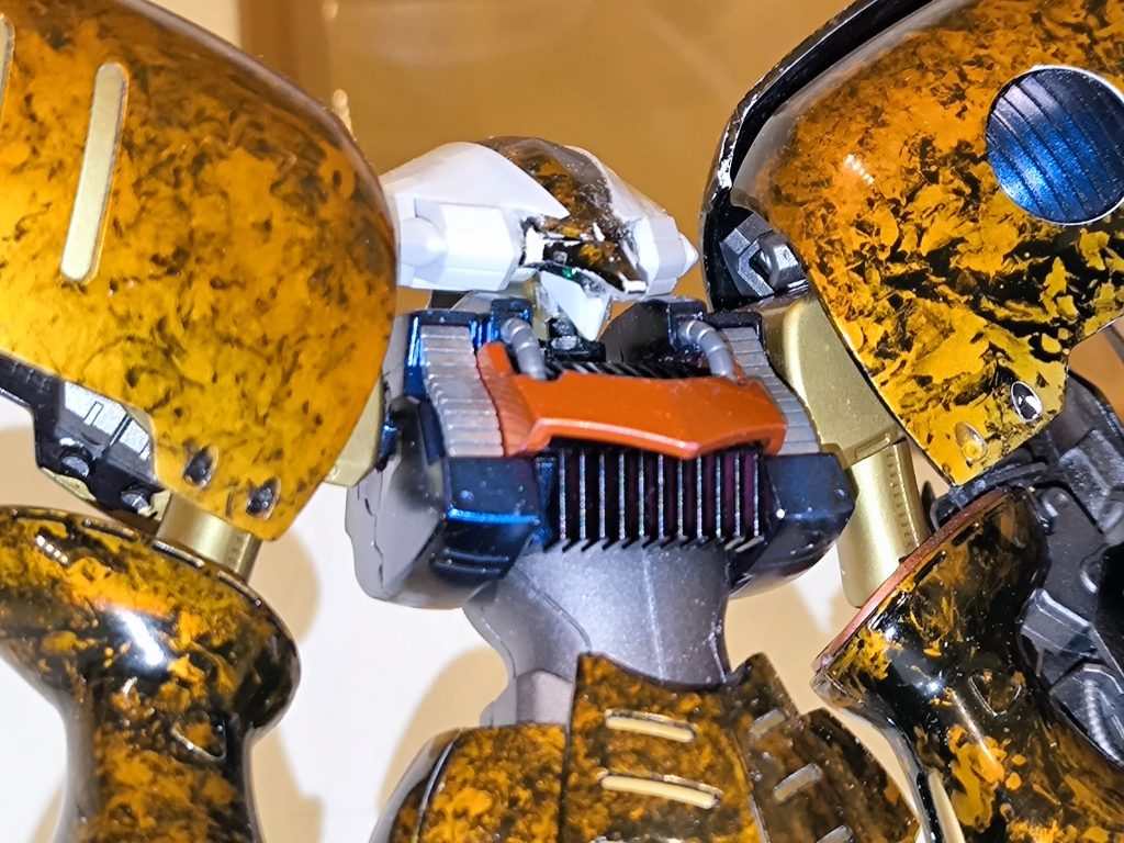 カメラアイを抜いた頭部パーツを上下接着、カメラアイパーツを基部として、プラ板とジャンクパーツでフェイスマスクを作成。ヘルメット部はプラ板とジャンクパーツで左右にボリュームアップしてます。