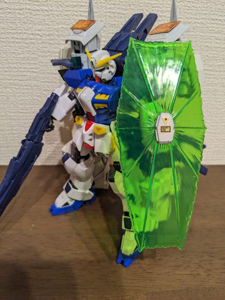 斜めからワンショット。ビームシールドと高出力ビームライフル。 肩のパック:光子収容タンクミノフスキー粒子が発散した際に発生する光子を探知、観測し、金のパネル部分からタンク内部に取り込み、機体エネルギーに変換するシステム。これにより継戦能力はほぼ無制限となる。(フォトンサーチャー、フォトンバッテリー) 肩先端のメタルグリーン部分:小型Iフィールド発生装置機体を覆うのではなく、高機動に機体関節が耐えられるよう、各関節をIフィールドバリアで保護するとともに、可動補助装置として利用する(Iフィールドビーム可動) ビームシールドは旧1/100F91のものをそのまま使用。ライフルはF91の後ろ部分にヴェスバーの前方部分を接着し、上下に旧1/144ターンエーのライフルを半分にして接着。光子タンクは旧1/100サーペントのバックパックに旧1/100エピオンのサイドスカートで蓋をしています。光子タンクと肩アーマーへの接続部分は旧1/100サンドロックカスタムのサイドスカートです。よく見ると光子タンクの横に、ターンエーの腕とサイドスカートを使ってもうひとつタンクが付いていますが、そこはまた後ほど…