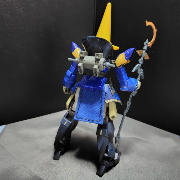 注）これはガンプラですよ……いやホント。デミトレーナーをメインにファイナルファンタジーシリーズの黒魔道士っぽいのを作っています。・肩アーマーや腰アーマーはクレオパトラキュベレイのを使用しています。・頭部はSDの部隊兵を使用し、そこに100均ショップで買ったカラーコーンを被せてます。※多少頭部を削るなどの加工をしています。・脚部はフェイクニューユニットの脚パーツを使ってます。※この部分は地味にいつものデミトレーナーの脚に換装できたりします。・杖は30MMの魔法セットを使ってます。この黒魔道士は最終的にFFⅨの黒のワルツ3号みたいに仕上げるつもりです。その為に、バックパックに翼パーツを装着できるようにするところです。（3枚目）