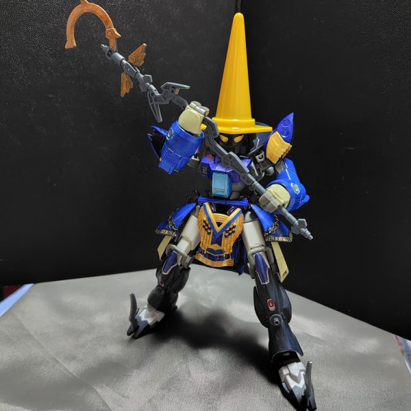 注）これはガンプラですよ……いやホント。デミトレーナーをメインにファイナルファンタジーシリーズの黒魔道士っぽいのを作っています。・肩アーマーや腰アーマーはクレオパトラキュベレイのを使用しています。・頭部はSDの部隊兵を使用し、そこに100均ショップで買ったカラーコーンを被せてます。※多少頭部を削るなどの加工をしています。・脚部はフェイクニューユニットの脚パーツを使ってます。※この部分は地味にいつものデミトレーナーの脚に換装できたりします。・杖は30MMの魔法セットを使ってます。この黒魔道士は最終的にFFⅨの黒のワルツ3号みたいに仕上げるつもりです。その為に、バックパックに翼パーツを装着できるようにするところです。（6枚目）