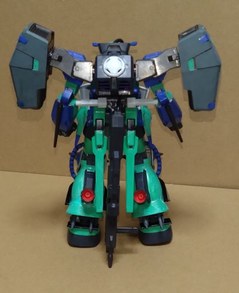 『GNZ（ガン・ズィ)』型式番号:GN-MS06NN宇宙世紀のザクに別世界（00）の技術を導入した機体。重武装によりパワーや防御は非常に高く、機動性と推進力はザクを超えるがあまり高くない。GN粒子によって重量は軽減されていることもあり、通常のザクより性能は超えている。『ガンダムに近づけたザク』と言っても過言ではない。名前は『GNドライヴ搭載ザク』の略で、別名はそのまま『GNザク』とも言える。ある程度ザクの原型を残した本機ではあるが、内側のフレームはもちろんコックピットも全天周囲モニターとなっている。しかし、操縦方法はほぼザクと変わらない設定。更にこの機体にはサイコミュも搭載されており、専用のファンネルも隠されている。本機にはGN粒子を備蓄するGNコンデンサーが内蔵されており、背中に常に装備されている『ヴァーチェパック』のGNドライヴと直接接続されている状態となっている。装備している間は動力がGNドライヴとなり、GNコンデンサーに粒子供給したまま戦うことが可能。バックパックを外した際は動力がコンデンサーへと代わり、貯蔵された粒子量がある間は戦い続けることができる。更に切り札とも言える『トランザムシステム』の使用も可だが、粒子量が一気に減ってしまう。GN粒子が無くなった場合でも、ザク本来のエンジンに切り替わって戦闘続行もできる。その場合、戦闘ステータスが一気に下がってしまうというデメリットもある。そんな機体だが、様々な世界のストライカーやシルエットを装備することで戦闘スタイルも大幅に変える。 パイロットは作品紹介で度々描いているストーリー『機動時空転移　ガンダムリベロ』のニノ・ニノマエ。民間のスペースノイドの少女で、唯一ザクを持っていた彼女はクロストラベラーのメンバーに入る。そんな彼女は自分が無力な存在だと落ち込む節を見せる中、メカニック担当のメモリーとカナのアイディアによりザクを改修した結果がこの姿なのだ。